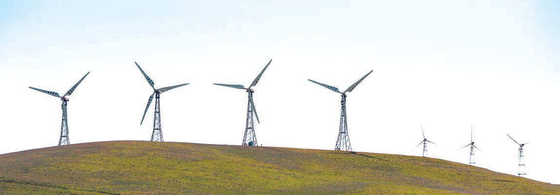 Windmills on mountain against clear sky